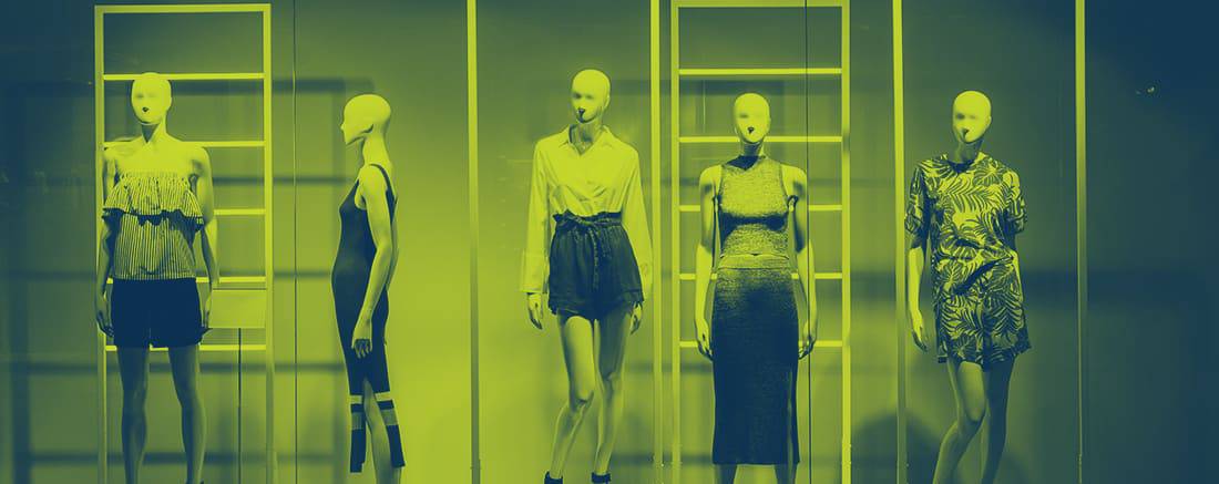 five mannequins standing in store window display
